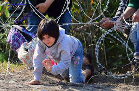 طفلة تعبر سياج حدودي بالاسلاك الشائكة مع اسرتها المهاجرة الى اوروبا.. شاهد الصور